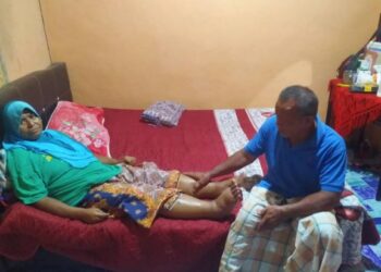 MOHD Amin Yahaya menunjukkan kedua belah kaki isterinya semakin membengkak sejak wanita itu disahkan mengalami penyakit buah pinggang tahap empat di Felda Kota Gelanggi Dua di Jerantut, Pahang. – UTUSAN/HARIS FADILAH AHMAD