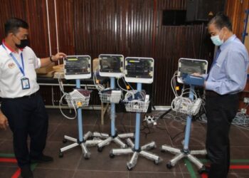 DR. ZAINI memeriksa mesin pemantauan tahap oksigen dalam darah yang ditempatkan di PKRC Gelanggang Seni, Kota Bharu yang akan beroperasi mulai Isnin. - UTUSAN/ROHANA MOHD. NAWI