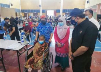 MOHD. Zuki Ali (kanan) melihat lelaki warga emas Orang Asli menerima suntikan vaksin di PPV Dewan Serbaguna Seri Iskandar, di Parit hari ini. - UTUSAN/MOHAMAD HAFIZI MOHD SAID