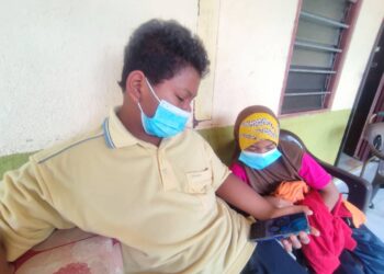 MUHAMMAD Syahmil Sabiha (tengah) bersama Nur Haniesya (kiri) menunjukkan gambar ibu dan bapa mereka yang meninggal dunia akibat Covid-19 baru-baru ini..-UTUSAN/NURULAZMA SHAFIQAH KHAIRUL AZHAR.