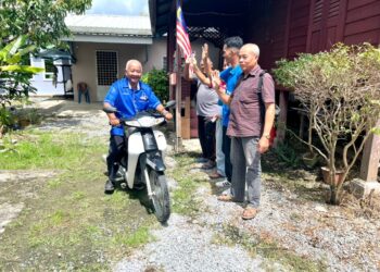 NURULHISHAM Yaakob (kanan) meneruskan rutin hariannya sejak dua penggal lalu menunggang motosikal bagi mendekati penduduk di Simpang Empat, Perlis.-UTUSAN/ASYRAF MUHAMMAD