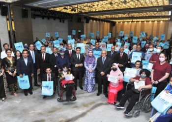 TAH Nia Jaman (berdiri, tengah) bersama Aminudin Adam dan Wan Munadi Wan Mamat bergambar bersama penerima sumbangan Khas Ziarah Kasih pada Mesyuarat Agung Tahunan Kali Ke-28 YGMB di Kota Kinabalu, Sabah.