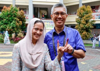 TENGKU Zafrul Tengku Abdul Aziz (kanan) bersama isterinya, Raja Johanna Adrina menunjukkan jari mereka yang dicelup dakwat mengundi di SK Puncak Alam 2, Kuala Selangor, Selangor.-UTUSAN/ AFIQ RAZALI