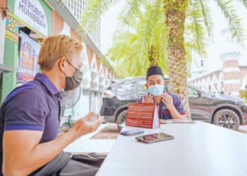 Muhammad Adib A.Rashid (kiri) mengaminkan doa selepas membayar zakat fitrah melalui pembantu 
amil, Muhammad Adeeb Nasharuddin di Masjid Jamek Kuala Lumpur, baru-baru ini.– UTUSAN/FARIS RUSADIO