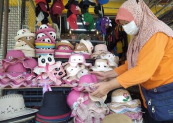 SITI Abdullah menyusun topi sambil menantikan kehadiran pengunjung di Medan Kraftangan Zoo Melaka, Ayer Keroh, Melaka. - UTUSAN/MUHAMMAD SHAHIZAM TAZALI
