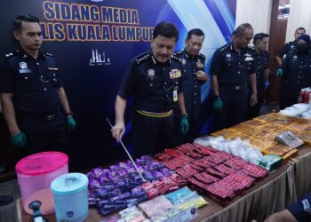 AZMI Abu Kassim melihat beberapa jenis dadah yang yang dirampas dalam sidang akhbar berhubung kejayaan menumpaskan tiga sindiket pengedaran dadah dengan nilai rampasan rm2.18 juta di Ibu Pejabat Polis Kontinjen Kuala Lumpur hari ini. - UTUSAN/FAUZI BAHARUDIN
